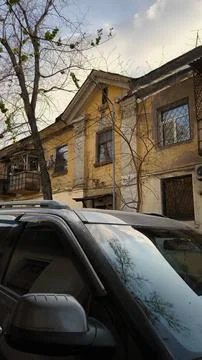 Reflection of trees in a car window against an old yellow building. Stock Photos