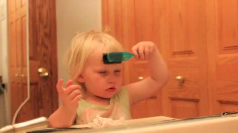 Reflection of a two year brushing her hair and looking for something Stock Footage 41651902