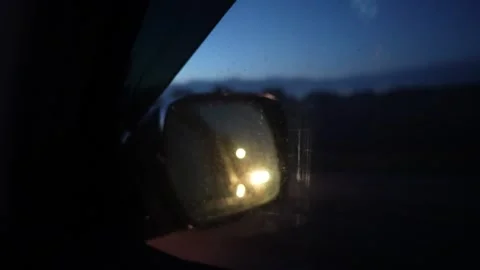 Reflection of vehicle headlights in side mirror during nighttime drive Stock Footage 319555528
