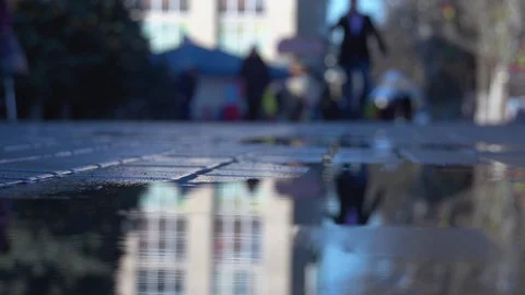 Reflection of walking people on the street in puddle Видео 101399983