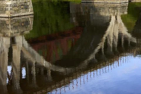 Reflection in the water of the old stone arch bridge Stock Photos