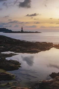 Reflection of water on the rocks on the beach, lighthouse on the coast even.. Stock-Fotos