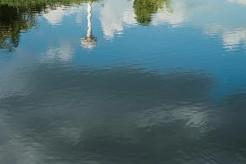 Reflection on the water of the sky, trees and water tower. Stock Photos