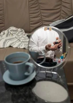 Reflection of well dressed man in white shirt in mirror on backdrop of home mess 스톡 사진
