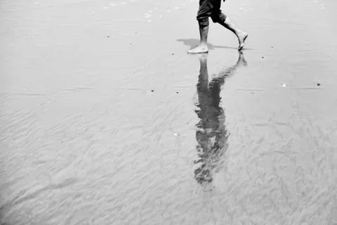 Reflection on the wet sand of a barefooted man. Sea beach Stock Photos