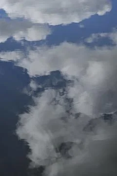 Reflection of white clouds and blue sky in rippling water Foto stock