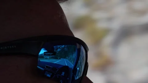 Reflection of winding mountain road in sunglasses Stock Footage 299896212