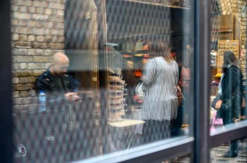 Reflection in a window of a man smoking a cigarette while using a phone Stock Photos