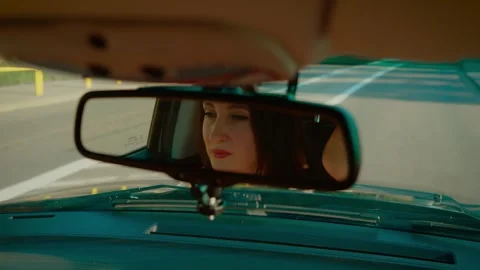 Reflection of woman in rearview mirror practicing driving with hands on steering Stock Footage 303433144