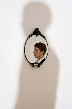 Reflection of young man in ornate mirror on wall Stock Photos