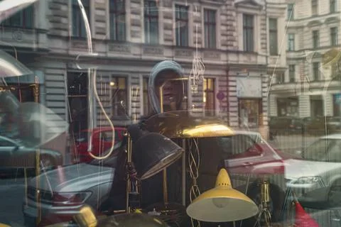 The reflection of a young man in a shop window with old lamps Stock Photos