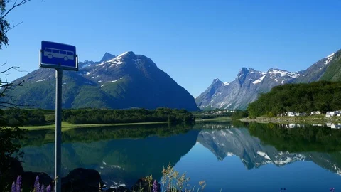 Reflections of beautiful mountains with snow, forest and a bus stop sign. Stock Footage 117401550