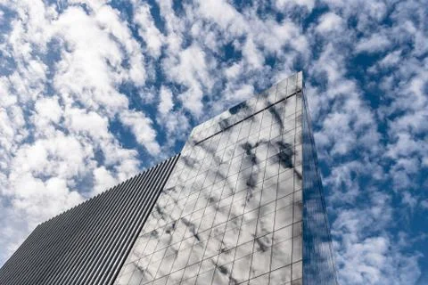 Reflections of clouds against modern skyscraper in New York Stock Photos