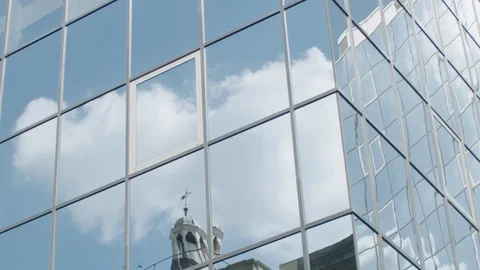 Reflections of clouds and sky and bell tower of an old building or church in Video stock 128781753