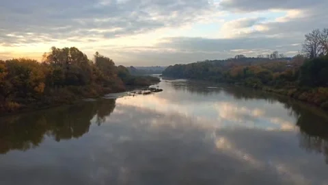 Reflections of clouds and trees along the banks of a wide river Stock Footage 317590327