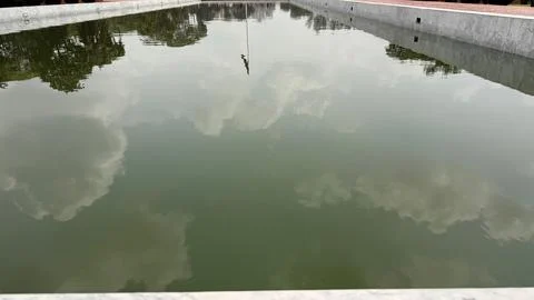 Reflections of clouds and trees are seen distinctly within the marble-lined r 스톡 사진