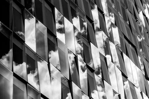 Reflections of cloudy sky on a glass facade Stock Photos
