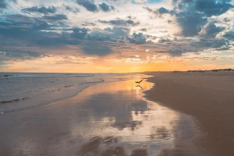 Reflections of dramatic clouds and vibrant sunset colors stretch across the.. Foto stock