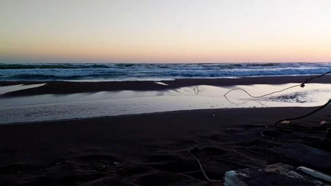 Reflections at Dusk: Soft Waves Beneath a Fiery Horizon Stock Footage 313920811