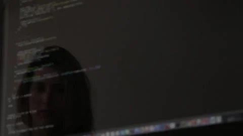 Reflections of a girl coding on a computer are visible on the screen or Stock Footage 281177554
