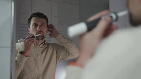 Reflections in mirror, man in shirt before work brushes his teeth with black Stock Footage 321426035