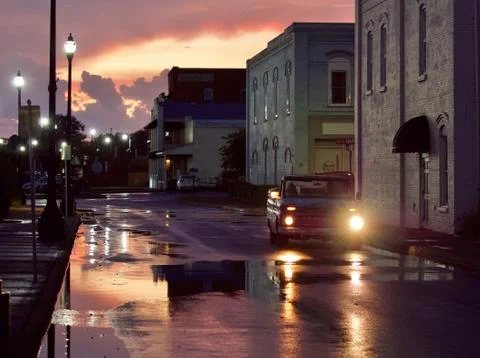 Reflections from the rain on a street at sunset Stock Photos
