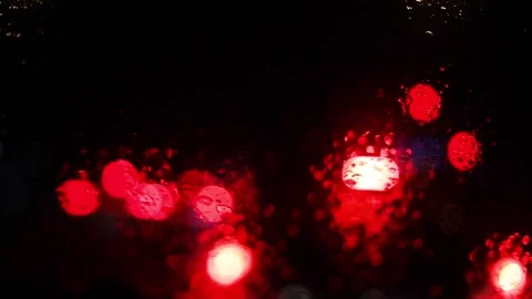 Reflections of red brake lights from the windshield of a car in heavy rain w Stockbeeldmateriaal 293100864