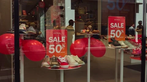 Reflections of shoppers in shoe store window advertising fifty percent sale Vídeos de archivo 340272756