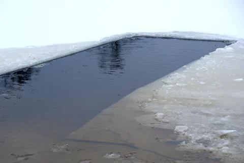 Reflections on a thawing pond surrounded by winter's embrace Foto stock