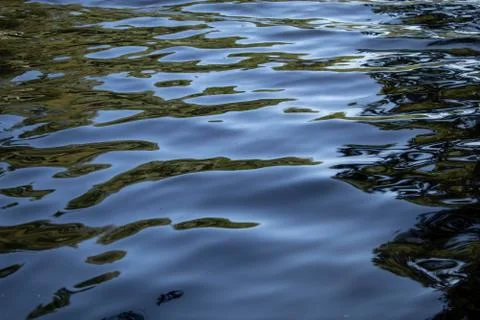 Reflections in the waves of deep black river water Stock Photos
