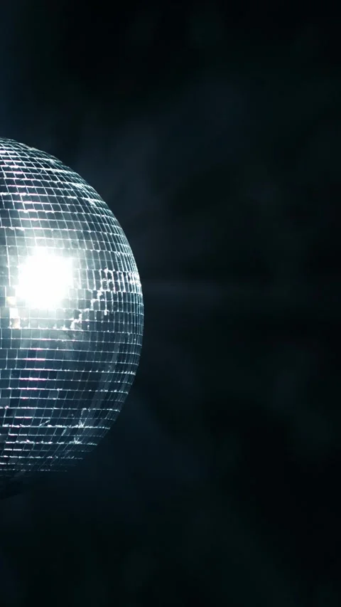 Reflective disco ball rotating against a dark background with blue light rays, Stock Footage 347734879