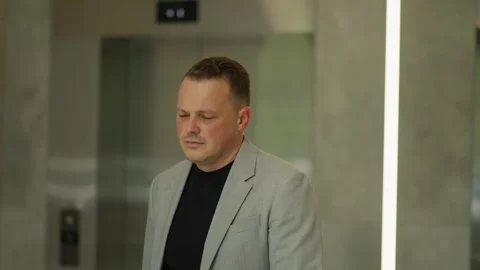 Reflective Executive in Midst of Busy Day. Businessman walks through elevator Stock Footage 270565690