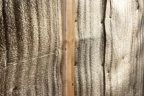 Reflective foil-faced insulation membrane installed on wooden stud for thermal Stock Photos
