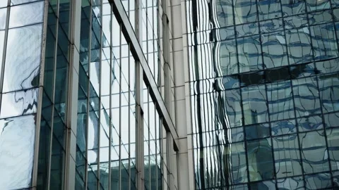 Reflective glass facade of a modern skyscraper showing distorted reflections of Stock Footage 327729414