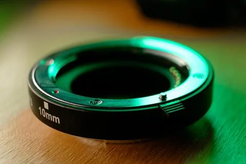 Reflective green light dances on a camera lens mount on a wooden surface Photos