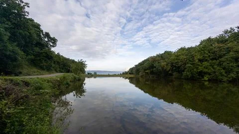 Reflective Lake Surrounded by Trees and Cloudy Sky Stock Photos