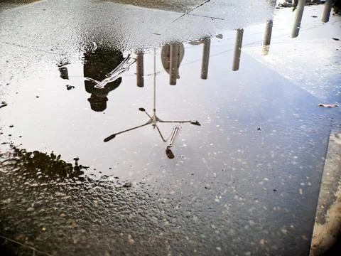 Reflective puddle mirrors abstract shapes and human figure in muted tones a.. 写真素材