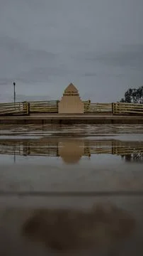 Reflective Puddle with Monument Under Cloudy Sky Stock Photos