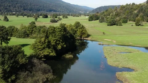 Reflective river winds through a lush valley, bordered by vibrant green fields. Stock Footage 287114075