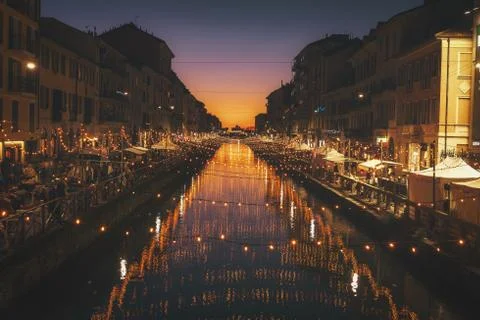 A reflective shot of string lights above river between the buildings during C Stock Photos