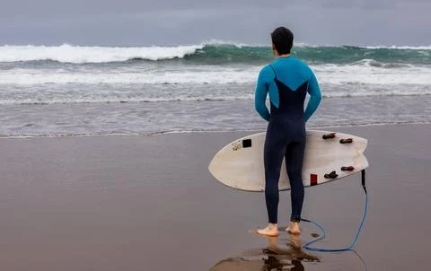Reflective surfer gazing at distant waves, copy space. Stock Photos