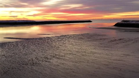Reflective tidal flat at sunset with a distant breakwater, aerial footage Видео 348625692