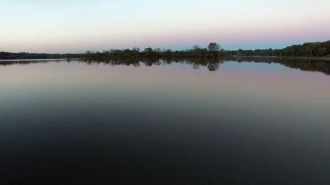 Reflective water camera moving towards island with trees close to water surface Stock Footage 72232755