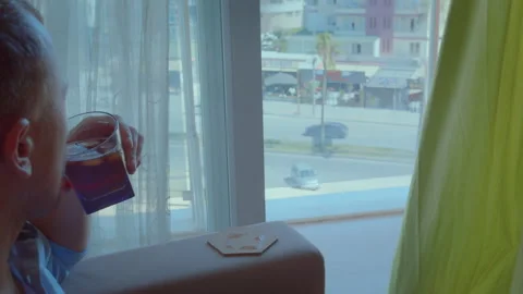 Reflective Young Man with Beverage by Window , Side Profile, Camera Tracking Stock Footage 303653064
