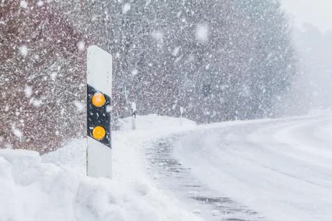Reflector post at white snow blizzard winter snowflakes road. The street trac Stock Photos