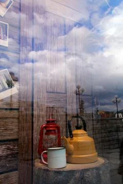 Reflex of the clouds and sky in the shopping window with cup of tea and tea k Stock Photos