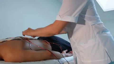 A reflexologist fixes electrodes on the patient's back for electrostimulation Stock Footage 116560788