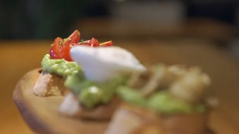 Refocus driving through three bruschettas on a cutting board, avocado toast with Vidéo 256143266