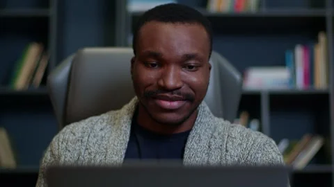 Refocus from the laptop to the face of a black man working online at home, a Видео 262851357