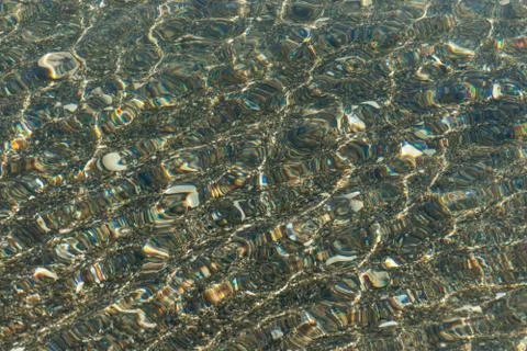 Refraction of light in clear water with small waves. Background Stock Photos